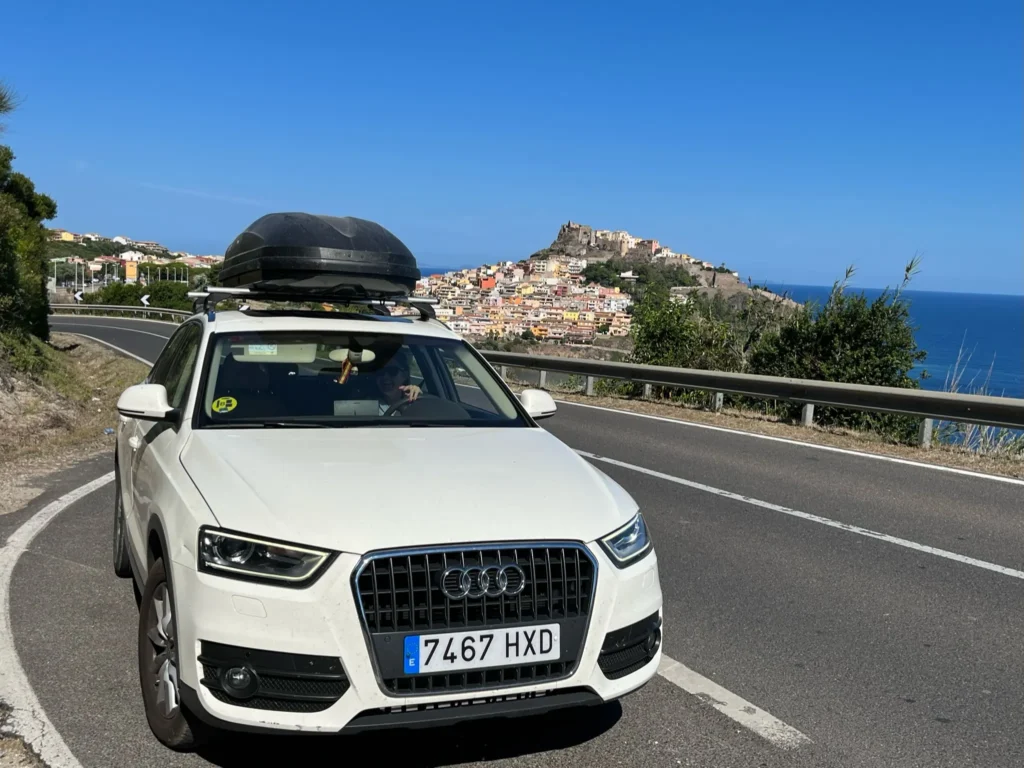 Coche aparcado con vistas al pueblo medieval de Castelsardo durante la ruta en coche por Cerdeña en familia