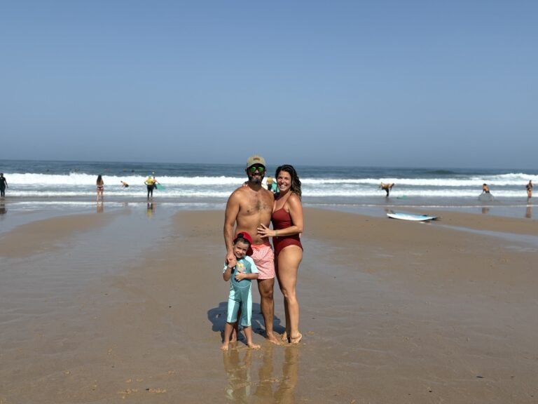 Familia feliz posando en la orilla de la playa de Vale Figueiras tras una sesión de surf.