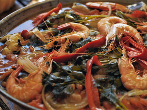 alt="Primer plano de una cataplana o guiso tradicional portugués con gambas frescas, pimientos y hierbas"