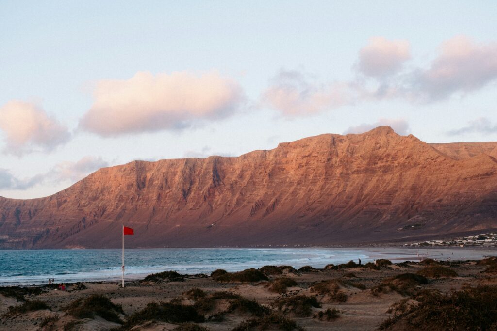 Vista panorámica de la playa de Famara en Lanzarote con el Risco de Famara al fondo y surfistas en el agua